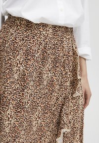 Leopardprint rok in beige, bruin en roestkleur, met een gesmokte tailleband en ruches aan de zijkant. Lichtgewicht stof.