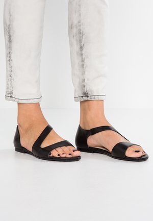 Sorte lædersandaler med åbne tæer, med to brede, flade remme tværs over foden og en lav, solid hæl. Glat tekstur, minimalistisk design.