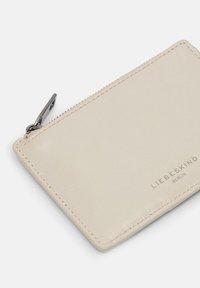 Portfel ze skóry w jasnobeżowym kolorze o gładkiej fakturze, wyposażony w zamek błyskawiczny i wytłoczone logo marki. Prostokątny kształt z subtelnymi przeszyciami.