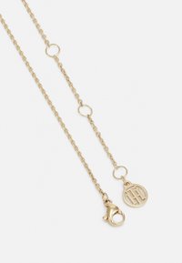Gouden ketting met een koningssluiting, ronde schakels en een hanger met een gestileerd monogramontwerp.