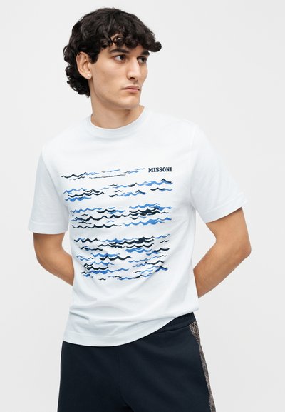 Λευκό T-shirt με μπλε και μαύρα κυματιστά σχέδια, με το λογότυπο «MISSONI». Κοντά μανίκια και κλασική στρογγυλή λαιμόκοψη.