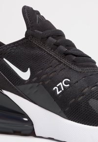 Scarpa sportiva nera con tomaia in mesh tessurizzato, caratterizzata dal logo Nike bianco, dal testo "270" e da una suola di gomma spessa nera e bianca.