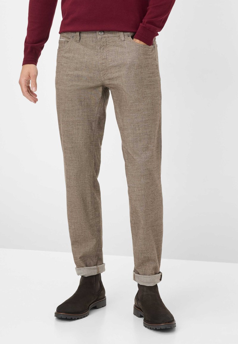 Pantaloni marroni con texture, dal taglio dritto, risvolti sulle caviglie e tasche frontali, abbinati a stivaletti marroni scuri.