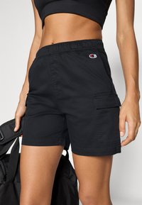 Svarta cargoshorts i lättviktig tyg, med elastisk midja, sidofickor och en logotypapplikation fram.