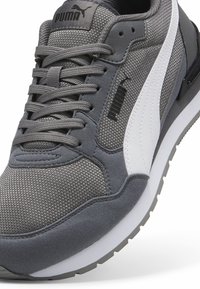 Baskets Puma grises avec bande latérale blanche, détails en mesh et en daim, lacets gris et logos Puma noirs sur la languette et sur le côté.