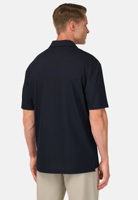 Polo de manga corta en color azul marino, confeccionado en una tela suave, con cuello clásico, aberturas laterales y un discreto detalle del logo en la parte posterior.