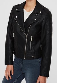 Giacca biker in ecopelle nera con colletto a revers, zip asimmetriche, dettagli imbottiti sulle spalle e particolari in metallo.