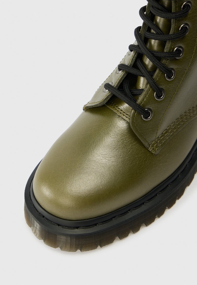 Grüne Leder-Ankle-Boots mit glänzender Oberfläche, versehen mit schwarzen Schnürsenkeln und Ösen, Gummisohle und genähten Akzenten an den Nähten.