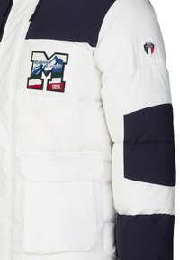 Daunenjacke mit einem weißen Körper und navyfarbenen Akzenten, großem gesticktem Logo und einer aufgesetzten Tasche auf der Vorderseite. Weiche Textur und gestepptes Design.