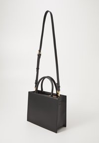Sac à main en cuir noir de forme rectangulaire, avec deux poignées supérieures et une bandoulière réglable. Présente des accents en métal doré.