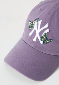 Lilla bomulds-baseballcap med hvidt broderet logo og grønne sommerfuglepåsyninger. Kappen har et struktureret design med en buet skygge.