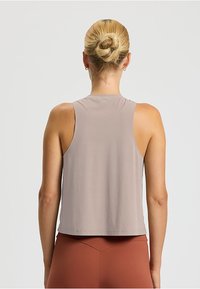 Top atletico senza maniche di colore marrone chiaro, con una vestibilità comoda, texture liscia e orlo arrotondato, progettato per garantire comfort durante gli allenamenti.