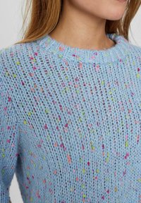 Helles blaues Strickpullover mit einem strukturierten Muster. Akzentuiert mit mehrfarbigen Sprenkeln in Pink, Grün und Orange. Mit Rundhalsausschnitt.