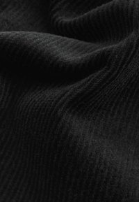 Tissu noir avec une surface douce et texturée présentant des stries subtiles et un léger éclat, mettant en valeur un tissage lisse et léger.