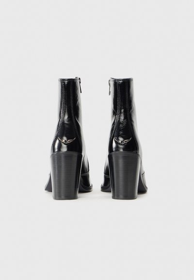 Svarta lackläder ankelboots med en smidig design, som har rundad tå, hög blockklack och dragkedja bakpå.