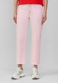 Jeans in denim rosa con taglio dritto, orli sfilacciati alle caviglie e vita con coulisse. Abbinati a sneakers grigie e bianche chunky.