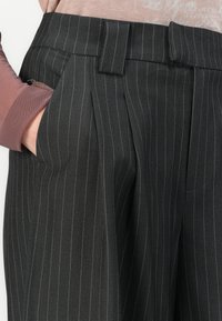Svarte pinstripe bukser med skreddersydd design, med frontfold, beltehempe i midjen og en glatt tekstur.