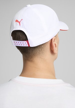 Biela baseballová čiapka s červenými akcentmi, na boku s logom Puma a textilným pásikom vzadu s ventilačnými otvormi.