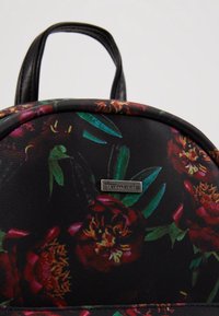 Sac à dos noir avec un motif floral rouge et orange, une poignée noire et une petite étiquette argentée de la marque "Tamaris" à l'avant.
