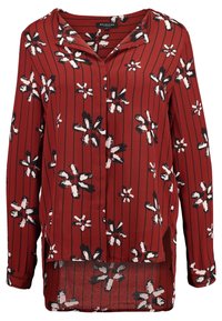 Blusa floreale rossa con motivi di fiori neri e bianchi, maniche lunghe, collo e righe verticali; tessuto leggero con una vestibilità morbida.