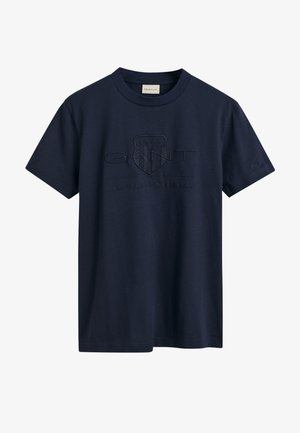 Granatowa bawełniana koszulka z krótkim rękawem, z teksturowanym logo i emblematem na przodzie. Prosty krój z okrągłym dekoltem.