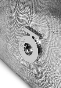 Borsa a tracolla in metallo argentato con texture a rete. Hardware argentato di rilievo comprende un logo circolare e un zip pull.