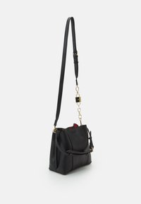 Borsa a mano nera in pelle con forma strutturata, caratterizzata da un'accattivante catena dorata, tracolla regolabile e un interno con un motivo colorato.