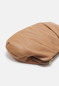 Pochette en cuir beige au design doux et plié. Dotée d'une fermeture éclair et de ferrures dorées. Texture lisse et forme arrondie.