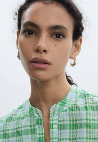Camicia a quadri verde e blu con colletto alla mandarino, realizzata in un tessuto leggero, con una sottile trama e bottoni color crema.