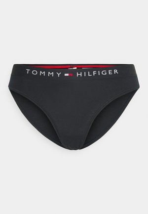 Slip bikini in cotone nero con una ampia cintura elastica decorata con il logo "TOMMY HILFIGER" nei colori bianco, rosso e blu. Tessuto liscio.