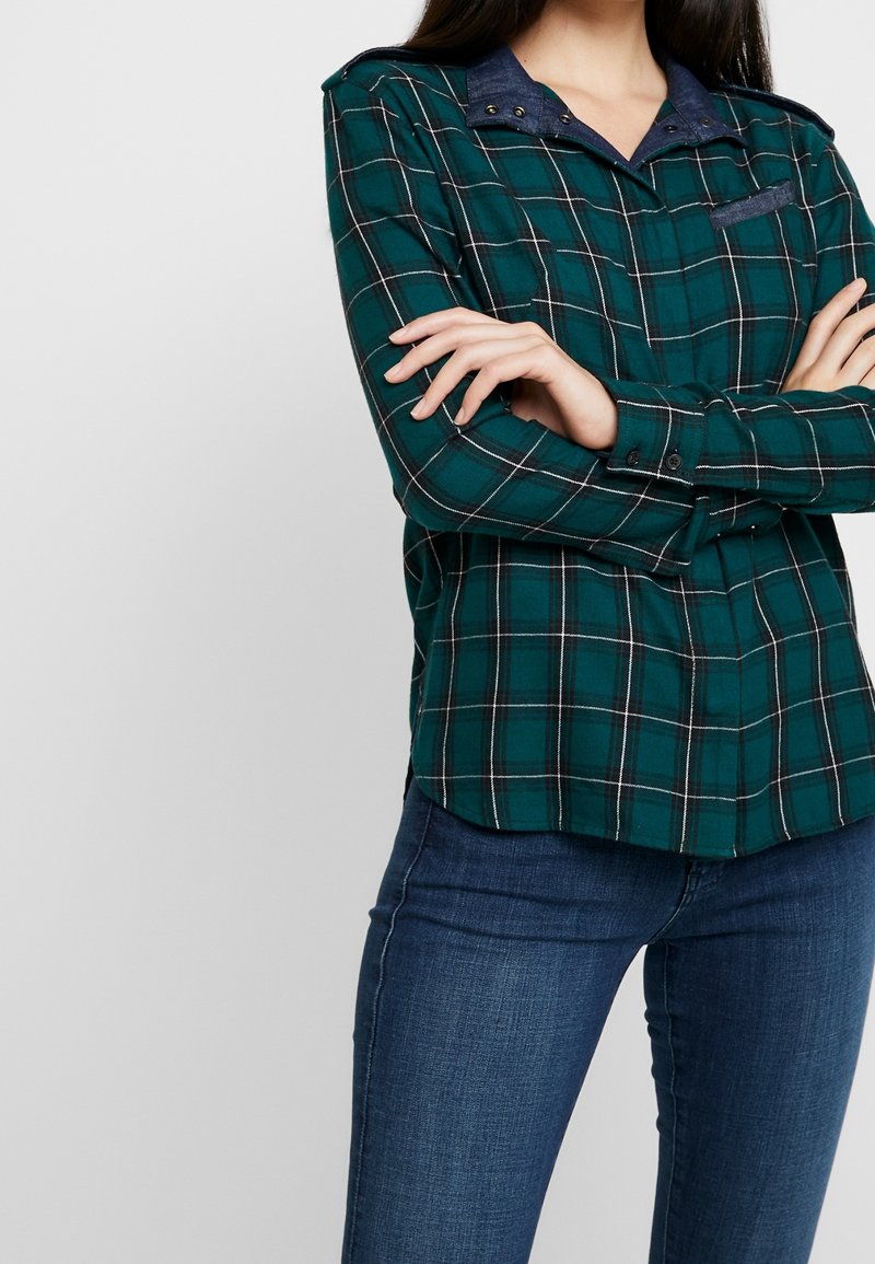 Grünes Karoshirt aus weichem Stoff mit einem Denim-Kragen und Schulterakzenten, mit geknöpften Manschetten und einer Brusttasche.