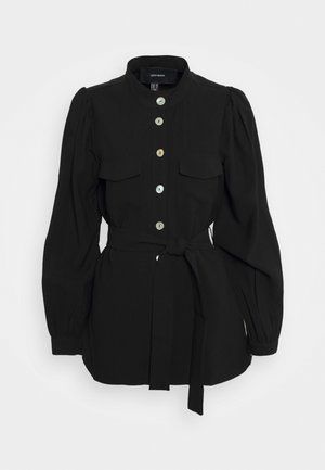 Black long-sleeve blouse with stand collar, button-down front, two chest pockets, puffed shoulders, and a waist tie belt.