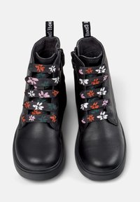 Botas de tobillo de cuero negro con cordones de patrón floral en rosa, blanco y naranja. Cuentan con una puntera redondeada y lengüetas para facilitar el calzado.