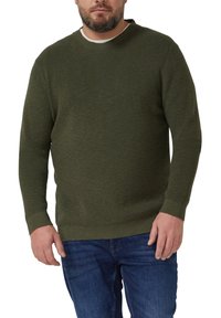 Ciemnozielony, teksturowany sweter dziany z okrągłym dekoltem i prążkowanymi mankietami, noszony na dżinsach. Prosty design bez widocznych wzorów ani zdobień.