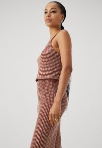 Ensemble deux pièces composé d'un haut sans manches et cropped et d'une jupe ajustée, réalisé en tissu tissé avec un motif zigzag rouge et blanc.