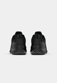 Schwarze Sportschuhe mit einem robusten Design, strukturiertem Obermaterial, verstärktem Absatz und gemusterter Gummisohle für einen guten Halt.