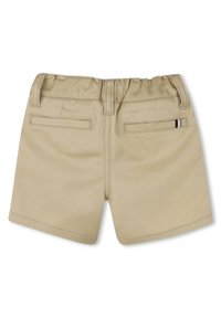 Shorts en coton beige avec une taille élastique, deux poches arrière et un détail rayé contrastant sur une poche. Texture lisse, design décontracté.