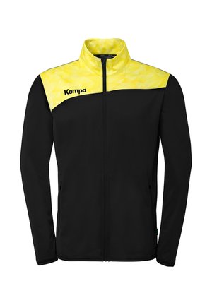 Zwarte jas met ritssluiting over de volle lengte, geel geometrisch patroon op de schouders en kraag, en het "Kempa"-logo op de linkerborst.