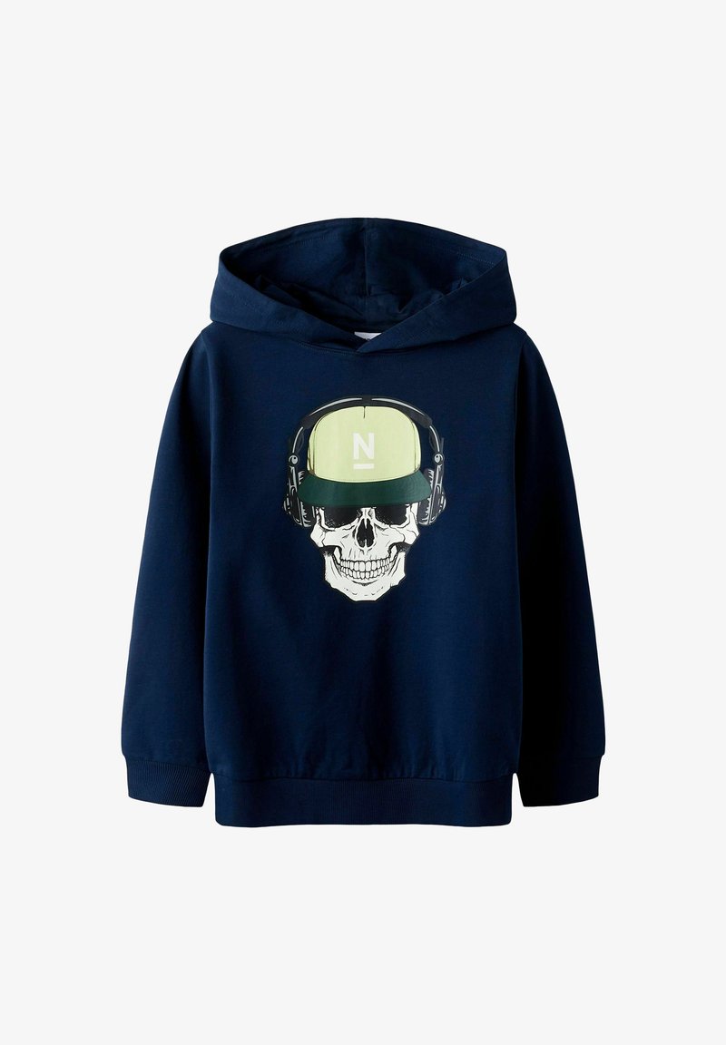 Tumši zils kapuce, kas izgatavota no mīkstas auduma, ar skeleta grafiku, kas valkā austiņas un zaļu cepuri ar baltu "N" logotipu.
