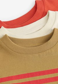 Drei gerippte Rundhals-T-Shirts: rostrot, cremefarben und olivgrün mit horizontalen roten Streifen. Baumwollstoff, lässiges Design.
