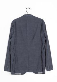Blazer grigio scuro con tessuto texturizzato, spacchi singoli sul retro e polsini con bottoni. Appeso a un gancio nero su uno sfondo bianco.