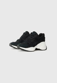 Sneaker nere con un mix di suede texturizzato e mesh. Presentano una suola bianca spessa, lacci neri e sottili accenti di glitter.