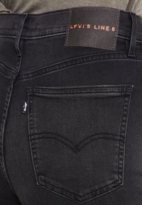 Černé džínsy z denimu s koženou nášivkou na zadní části s logem "LEVI'S LINE 8". Výrazné zakřivené prošívání na zadní kapse pro detail.