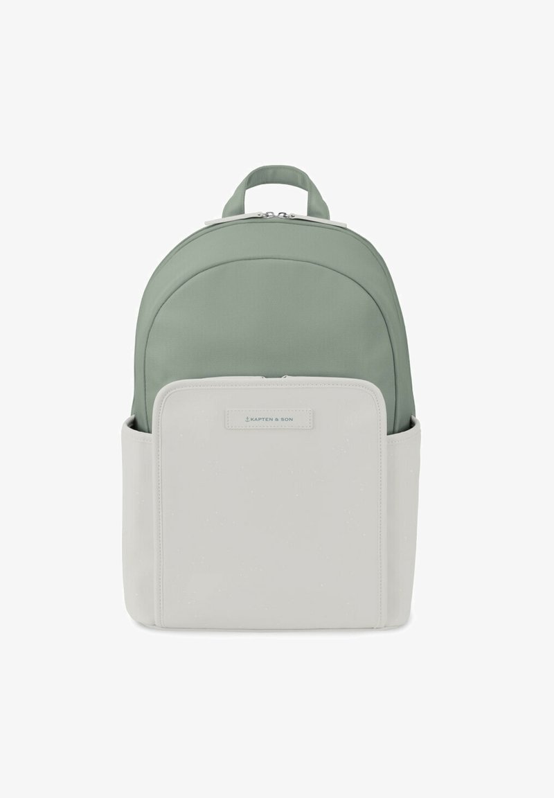Sac à dos en tissu vert doux avec un fond en cuir blanc lisse. Il dispose d'une poche avant, d'une forme arrondie et d'une poignée de transport en haut.