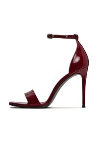 Sandale à talon haut en cuir verni rouge avec une large sangle unique et une boucle à la cheville. Présente un bout pointu et un talon aiguille fin.