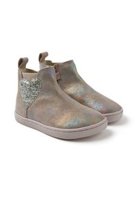 Botines de tobillo beige brillantes con un detalle de corazón plateado brillante, paneles laterales elásticos y una suela de goma texturizada.