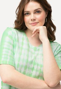 Zeleno-bílý tričko s krátkým rukávem ve stylu tie-dye s ribkovanou texturou a designem do V. Měkký materiál s volným střihem a výraznými barevnými vzory.