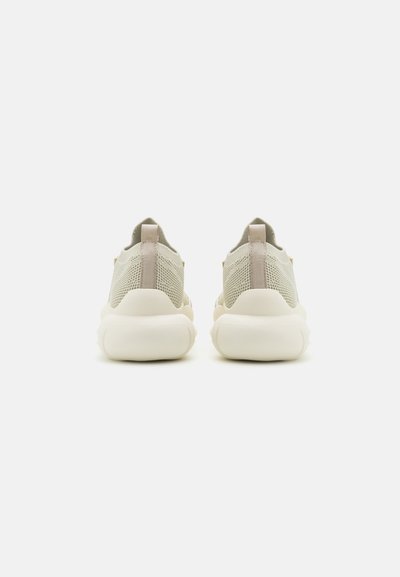 Light beige sneakers with a mesh upper, rounded toe, and cushioned white sole. Features a subtle back loop for easy wear.