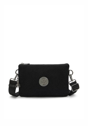 Sort tekstil crossbody taske med en glat overflade, som har sølvhardware, et rundt logo-patch og en justerbar rem.