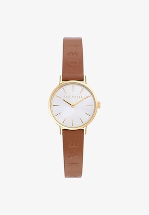Montre ronde avec un boîtier en or, un cadran blanc et un bracelet en cuir marron avec un logo embossé sur la sangle. Design minimaliste et marquages.